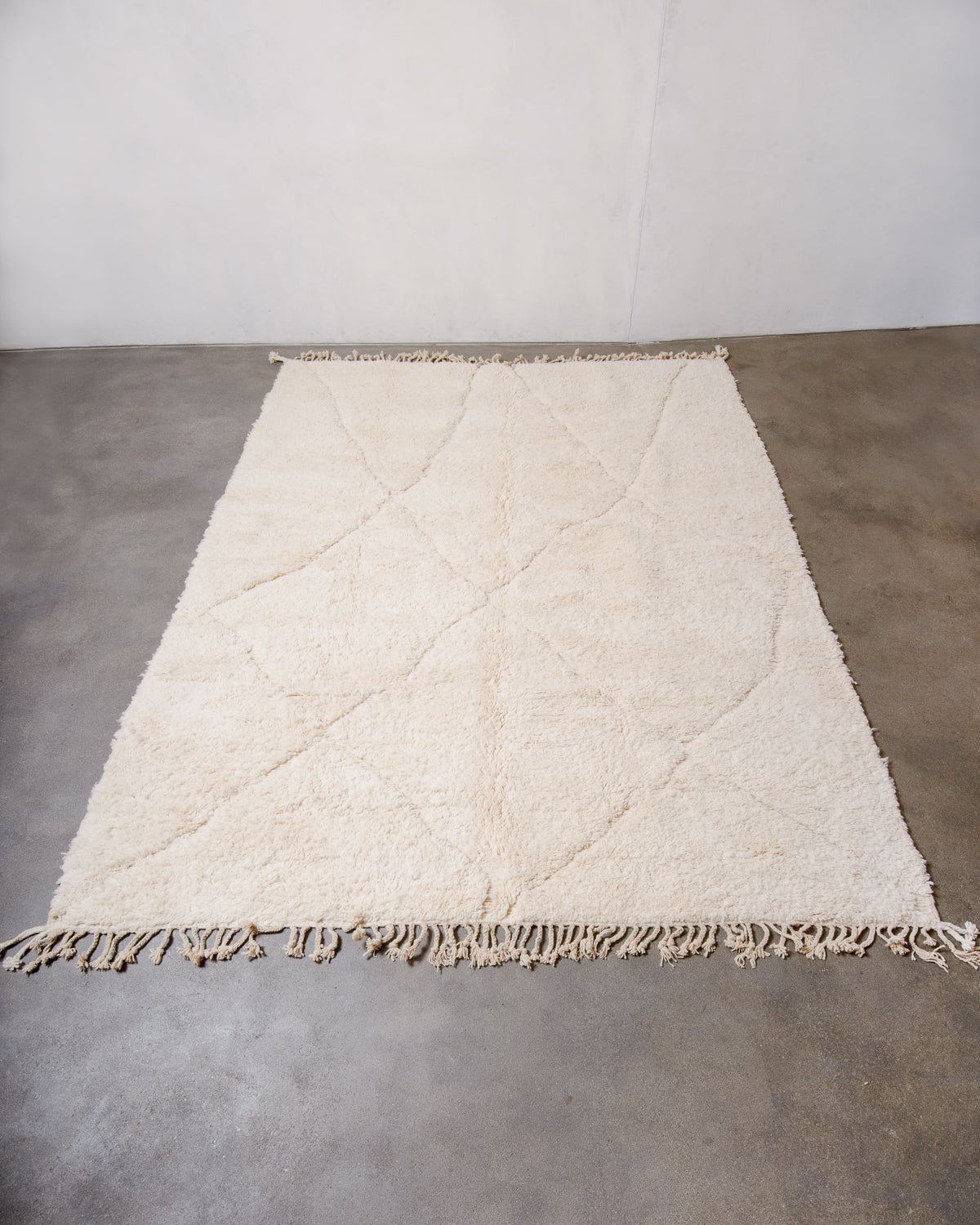 Berberlin Beniourain rug made of cream wool laying flat on concrete floor.